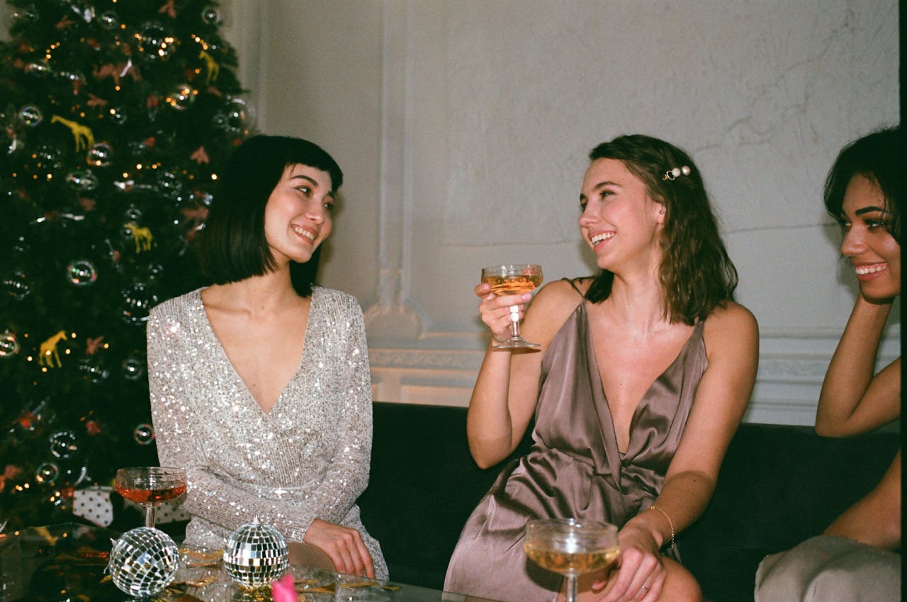 Three women enjoying festive celebration indoors with cocktails and joy.